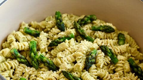 A large stockpot containing Cheesy Asparagus Pesto Pasta with fresh asparagus pieces