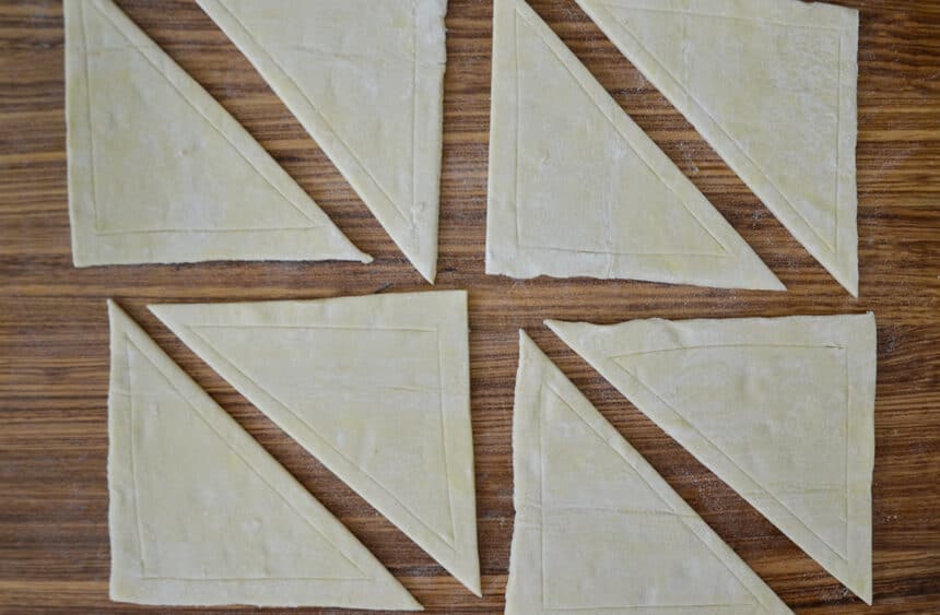 Triangles of puff pastry on a wooden cutting board