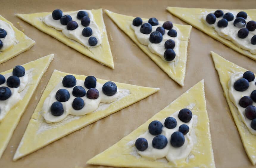 Unbaked triangles of puff pastry topped with lemony cream cheese and fresh blueberries