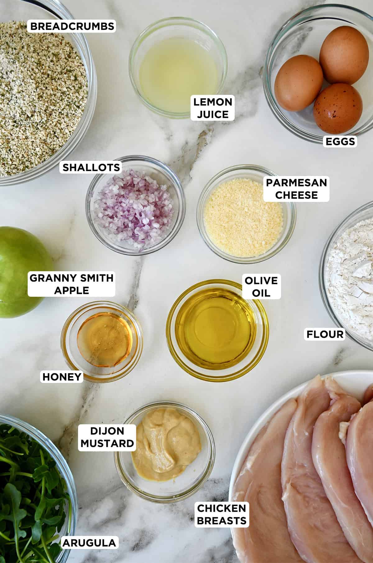 Glass bowls containing chicken Milanese ingredients.