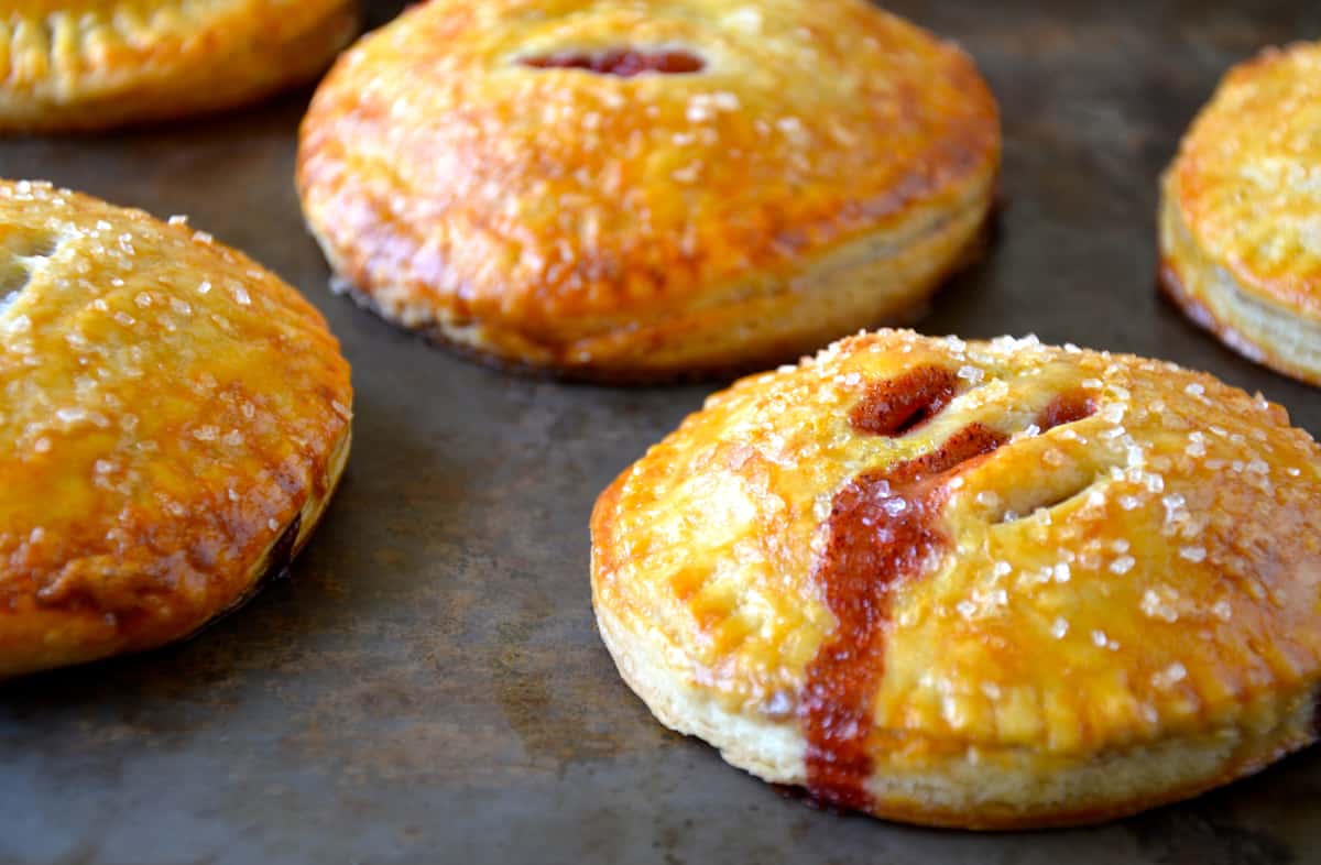 Strawberry jam oozy from a baked hand pie that's been topped with sanding sugar.