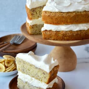 A slice of banana cake with cream cheese frosting on a plate