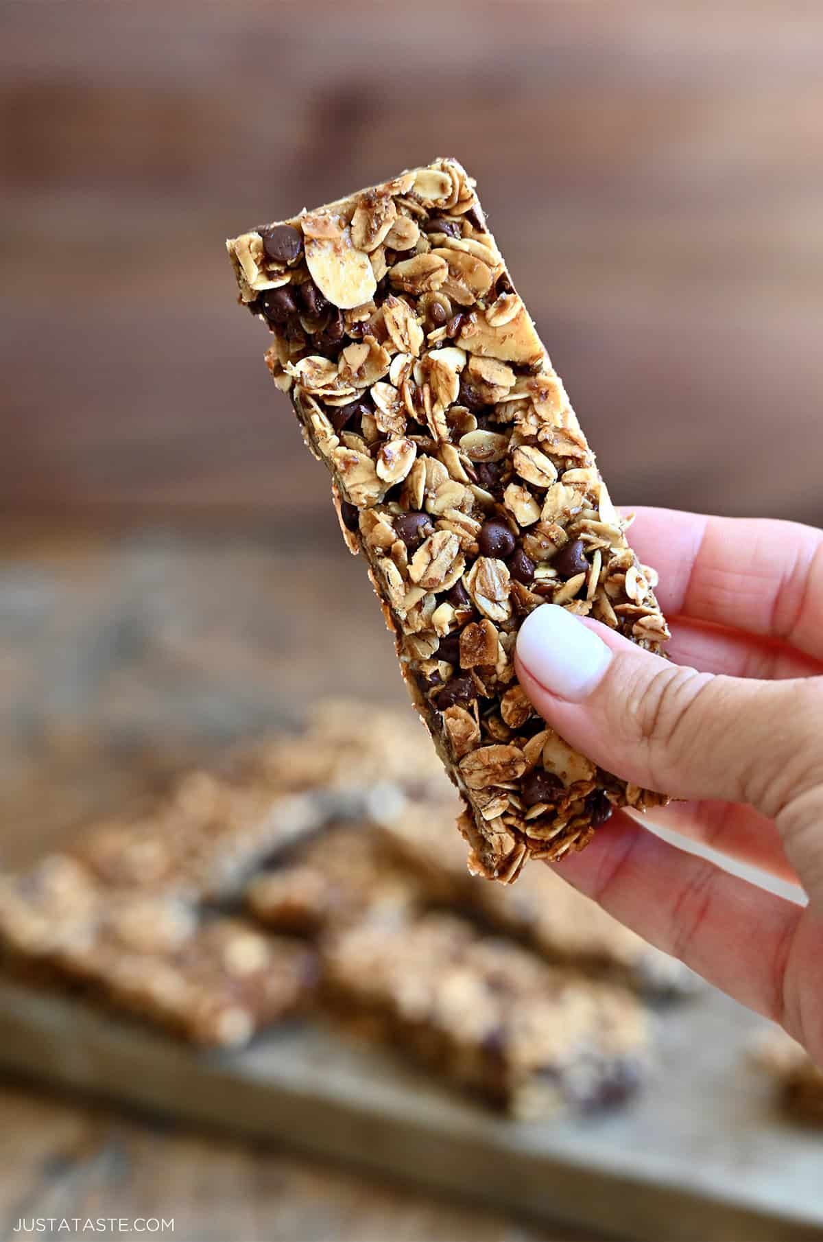 A hand holds a homemade chewy chocolate chip granola bar.