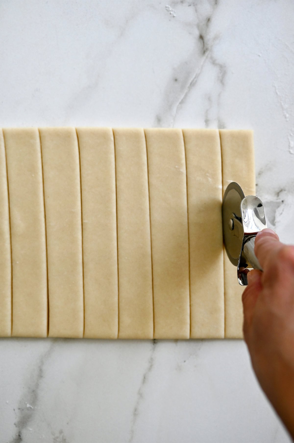 Cutting pie dough into perfect strips by using a pizza wheel.