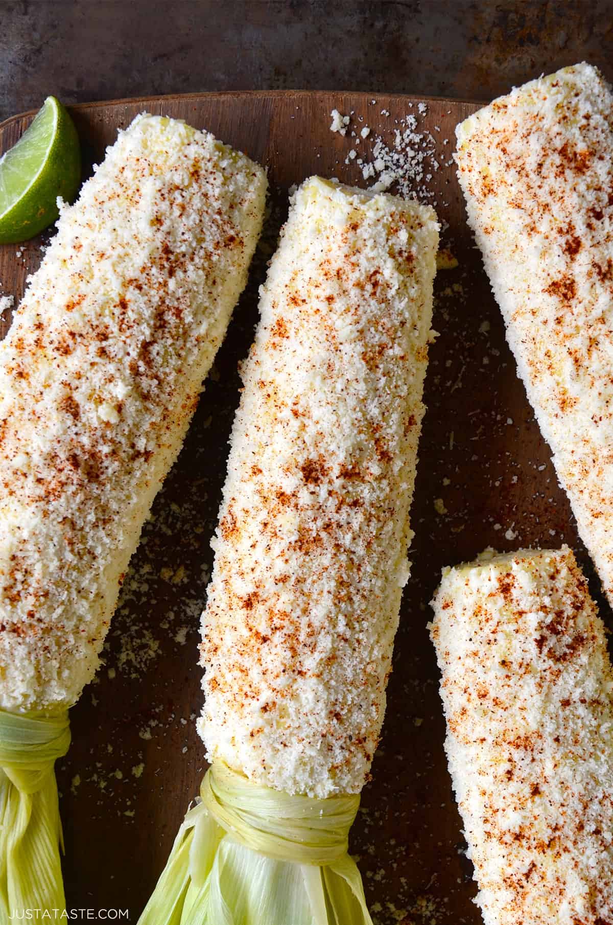 Mexican street corn (elote) slathered in creamy sauce, coated in crumbled Cotija cheese, and sprinkled with chili powder.