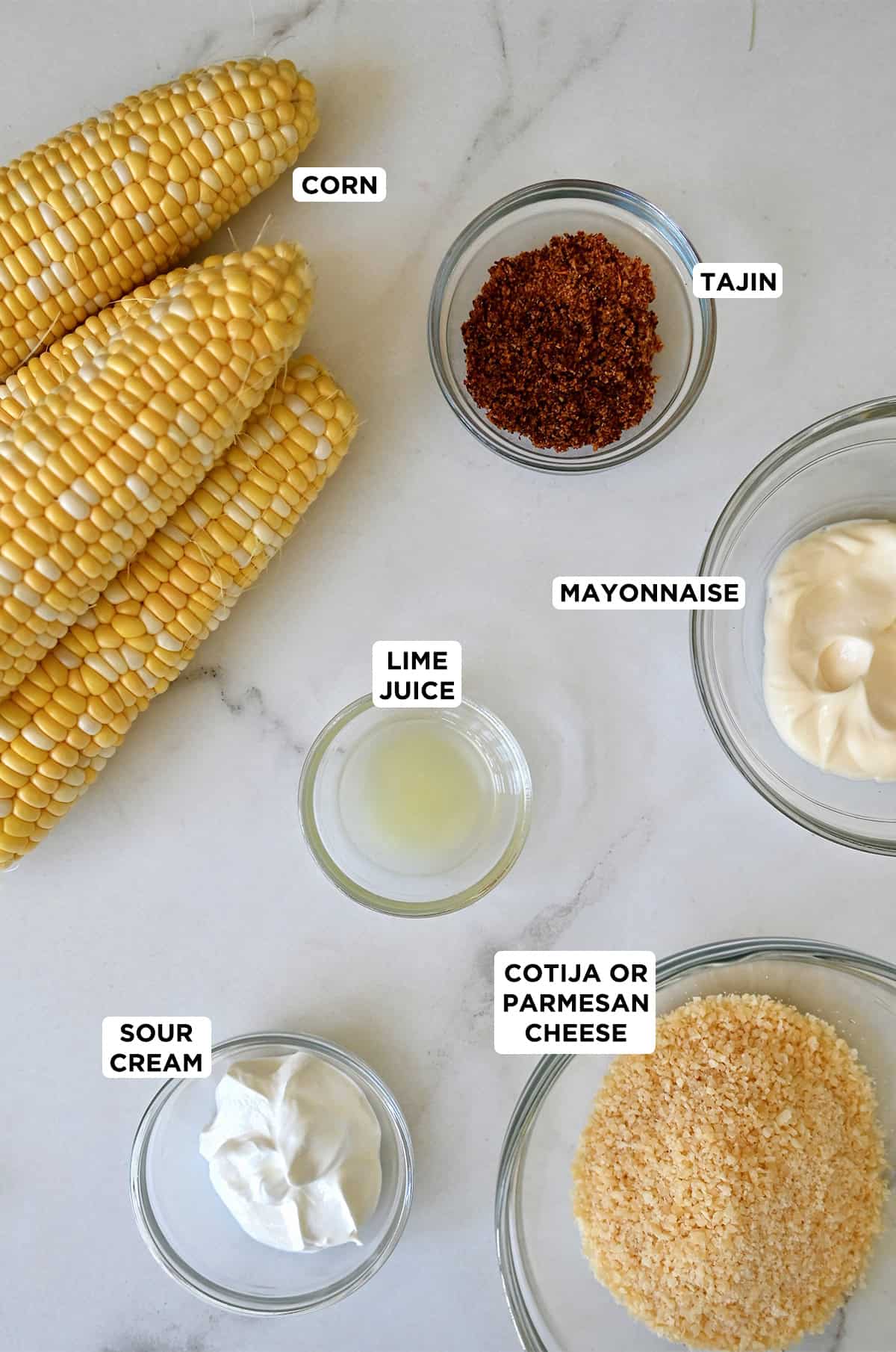 Ingredients to make Mexican street corn: sweet corn on the cob, mayo, sour cream, Cotija cheese, lime juice and chili powder.