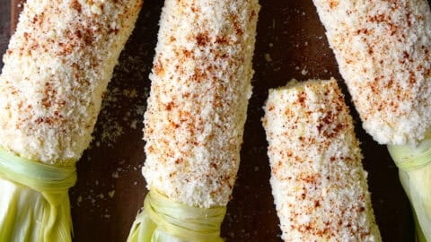 Four elotes or Mexican street corn, which is corn on the cob slathered with a mixture of mayo, Mexican crema and lime juice then rolled in Cotija cheese and sprinkled with chili powder.