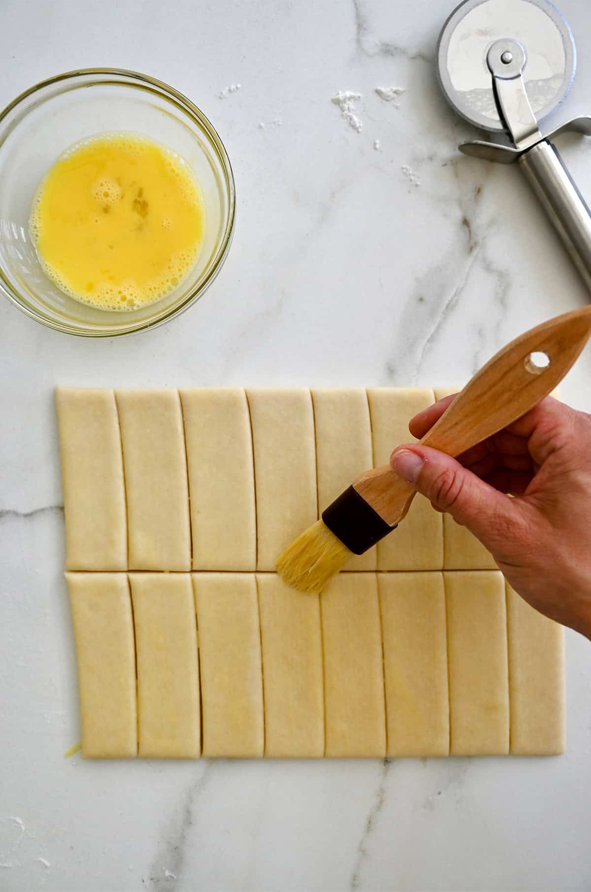 Adding an egg wash to pie dough with a pastry brush.