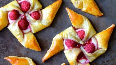 Raspberry cream cheese pinwheel pastries on a dark marble countertop.