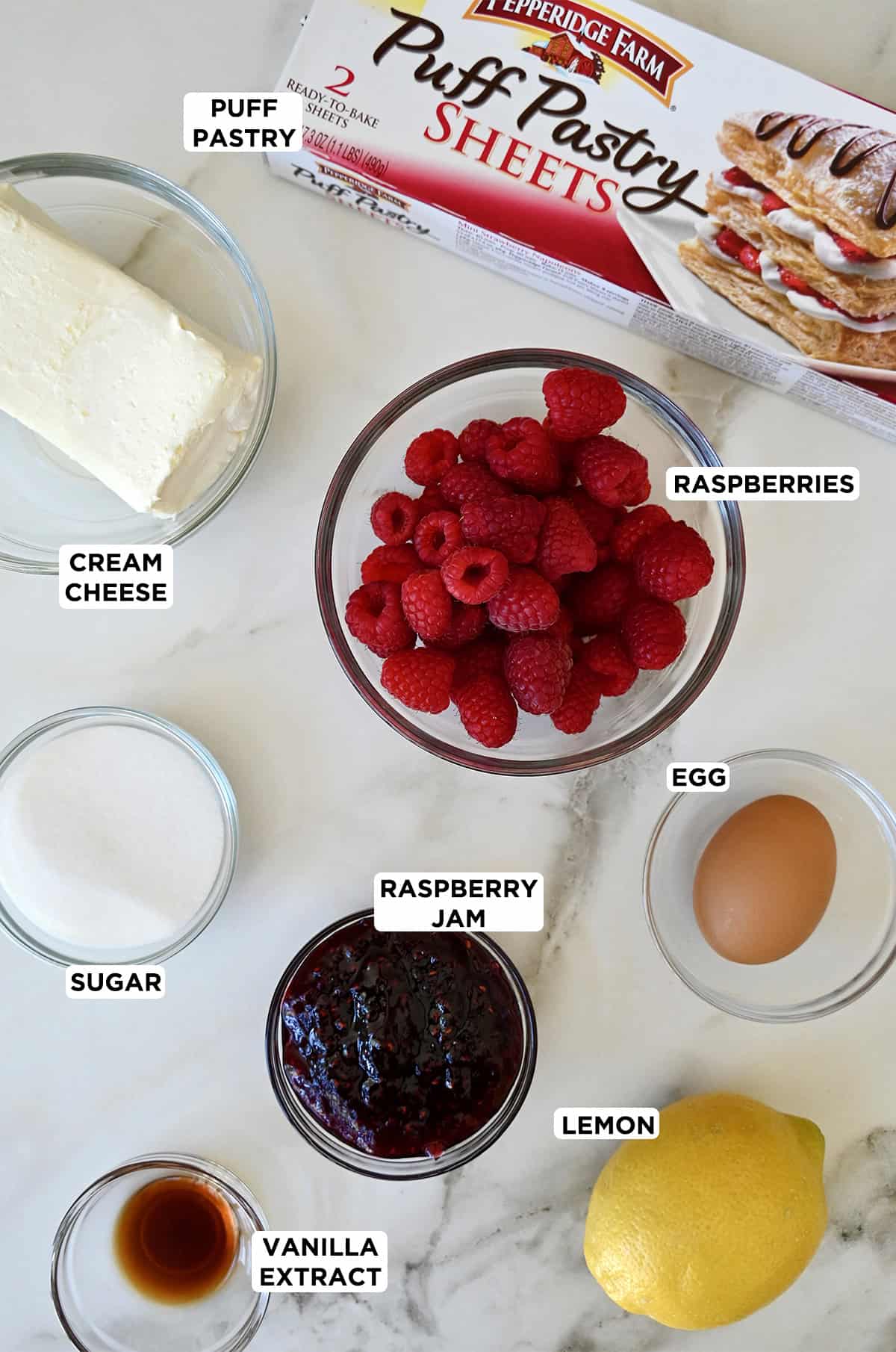 Raspberry cream cheese pastry ingredients, including frozen puff pastry sheets, cream cheese and fresh raspberries.