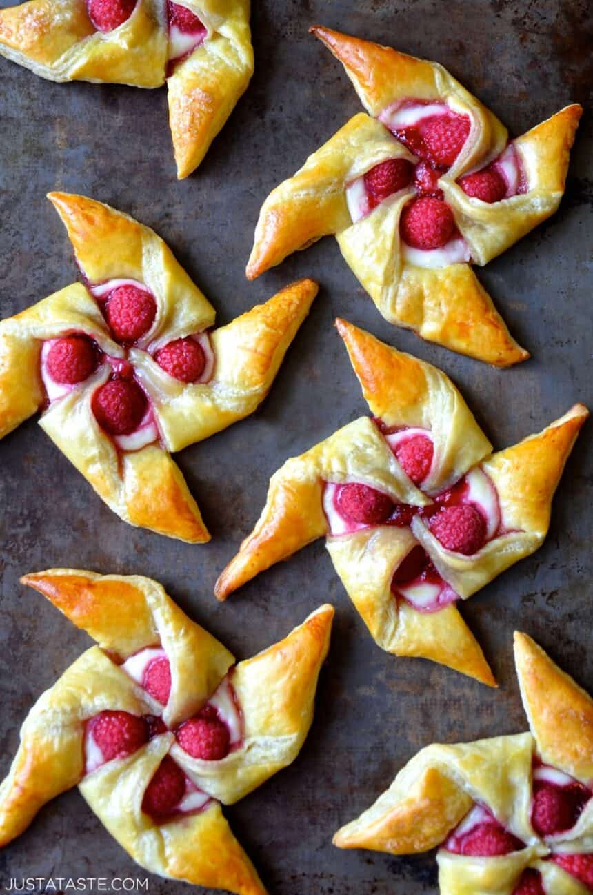 A top-down view of Raspberry Cream Cheese Pinwheel Pastries on a dark surface 