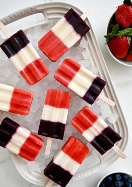 A white platter topped with crushed ice and red, white and blue popsicles