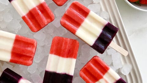 A white platter topped with crushed ice and red, white and blue popsicles