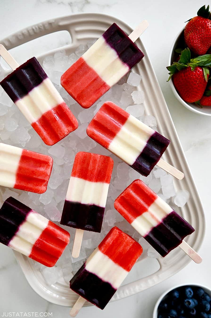 A white platter topped with crushed ice and red, white and blue popsicles