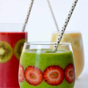 Three types of fruit smoothies in glasses with fruit stuck inside