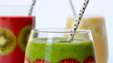 Three types of fruit smoothies in glasses with fruit stuck inside