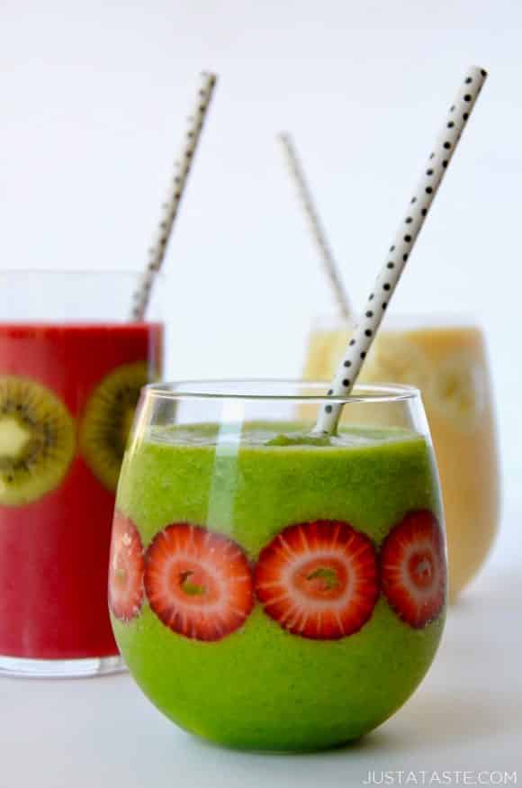 Three types of fruit smoothies in glasses with fruit stuck inside