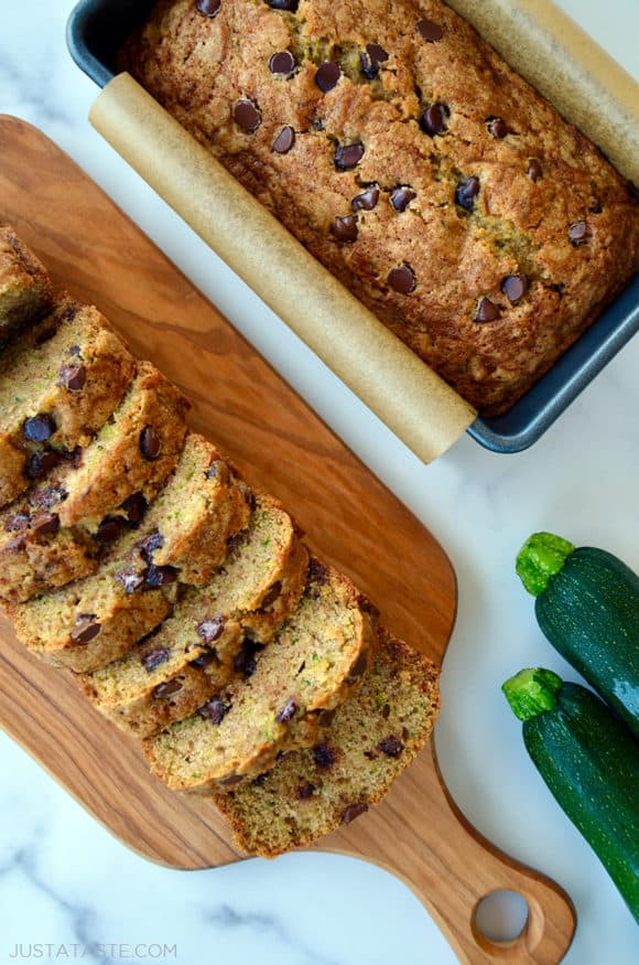 One loaf of Zucchini Chocolate Chip Bread sliced next to another loaf in a parchment paper-lined bread pan
