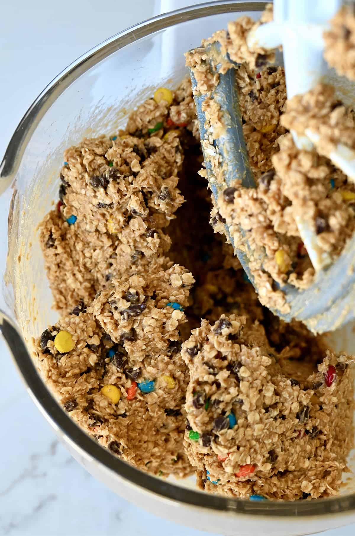 Monster cookie bar dough in the bowl of a stand mixer with the paddle attachment.
