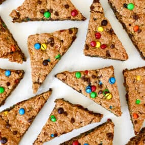 Monster cookie bars studded with M&Ms and chocolate chips cut into triangles.