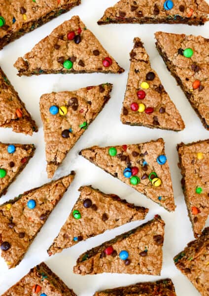 Monster cookie bars studded with M&Ms and chocolate chips cut into triangles.
