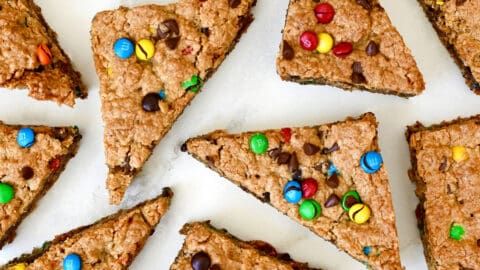 Monster cookie bars studded with M&Ms and chocolate chips cut into triangles.