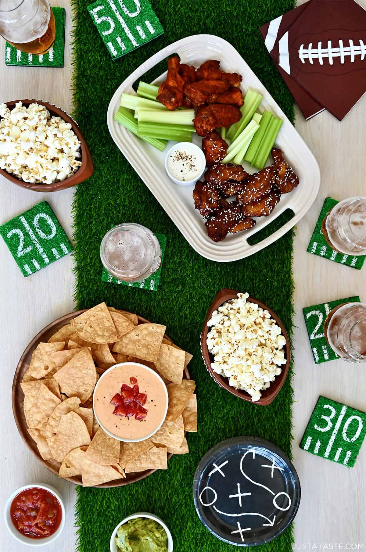 A top-down view of a tablescape with an astroturf runner and football snack foods