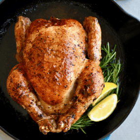 Simple roast chicken with rosemary and lemon in a cast iron skillet.