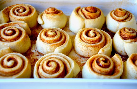 Baked cinnamon rolls close up in a white baking pan