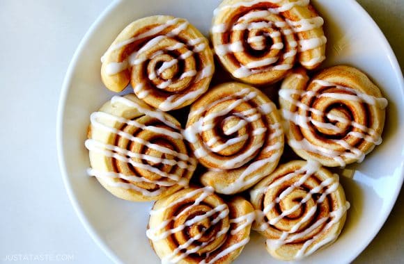 Cinnamon rolls arranged on a white plate and topped with icing