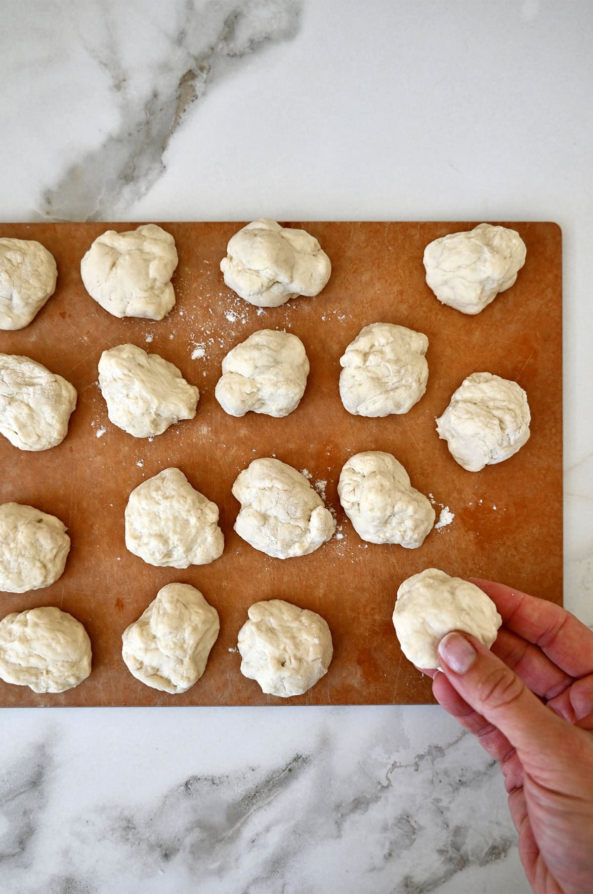 Small pizza dough balls on a cutting board.