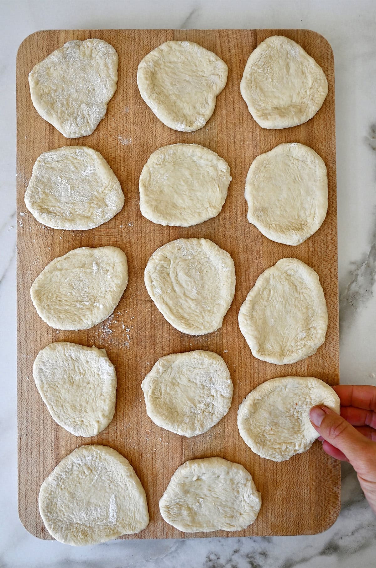 Flattened pizza dough balls on a cutting board.