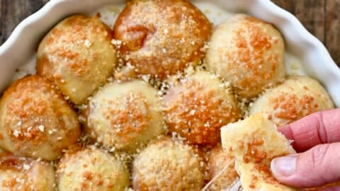 A pizza bite being pulled apart to expose the gooey mozzarella cheese and pepperoni center.