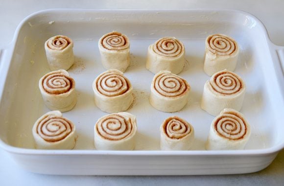 Unbaked cinnamon rolls in a white baking pan