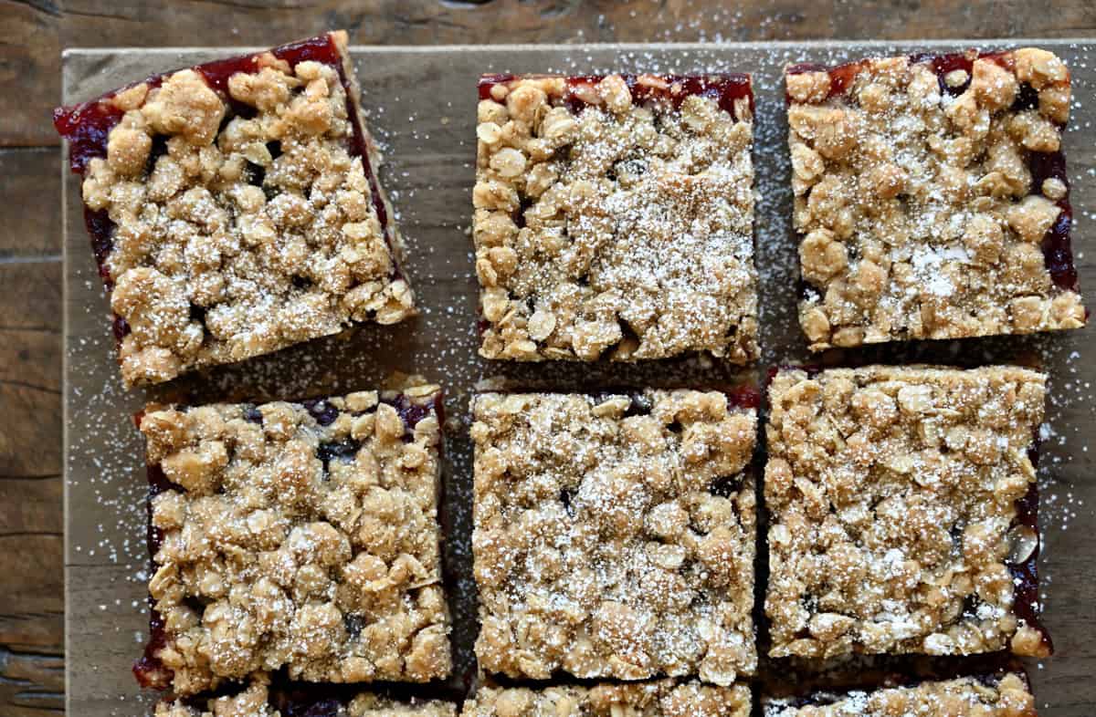 Cranberry crumb bars dusted with powdered sugar on a serving platter.