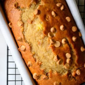 Peanut butter banana bread studded with peanut butter chips in a parchment paper-lined loaf pan.