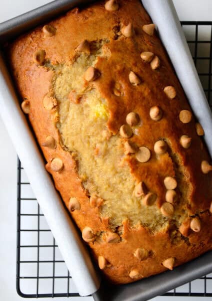 Peanut butter banana bread studded with peanut butter chips in a parchment paper-lined loaf pan.