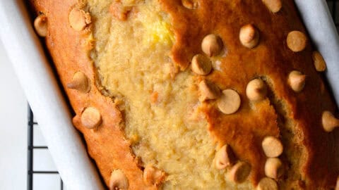 Peanut butter banana bread studded with peanut butter chips in a parchment paper-lined loaf pan.