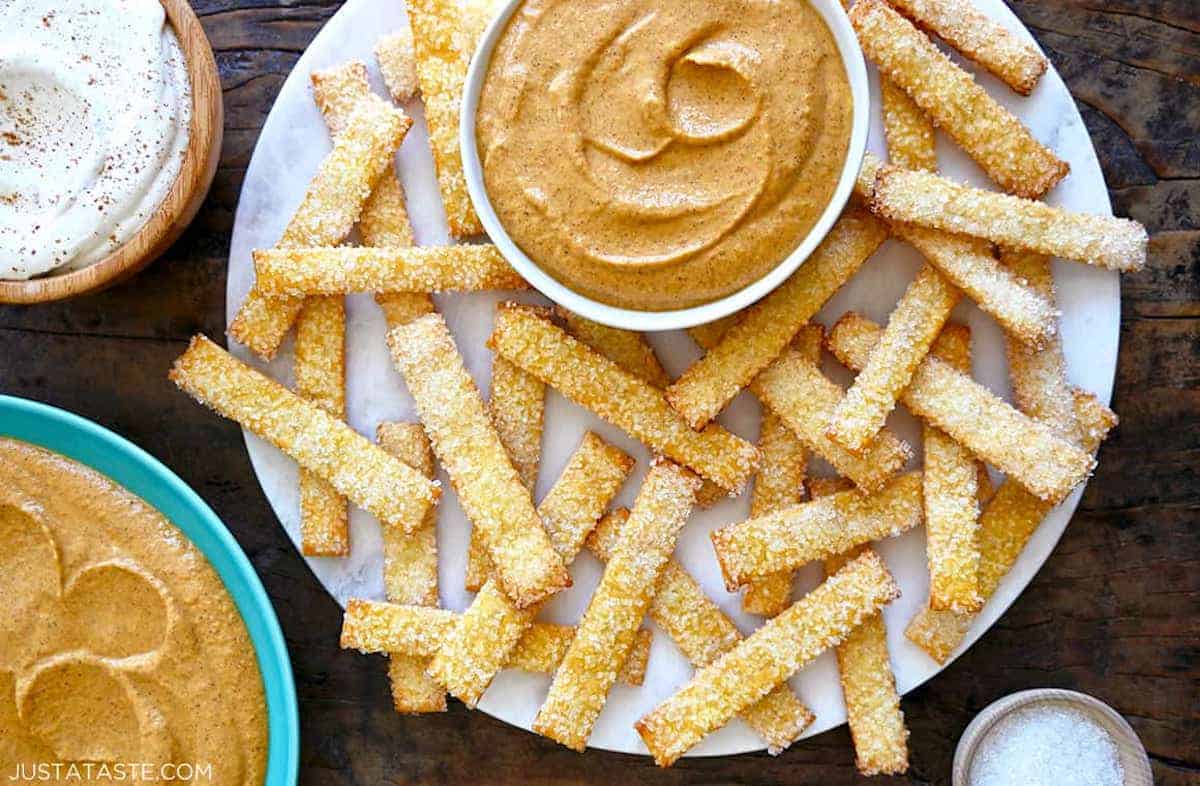 Pumpkin fries on a white plate with a small bowl containing cream cheese pumpkin dip.