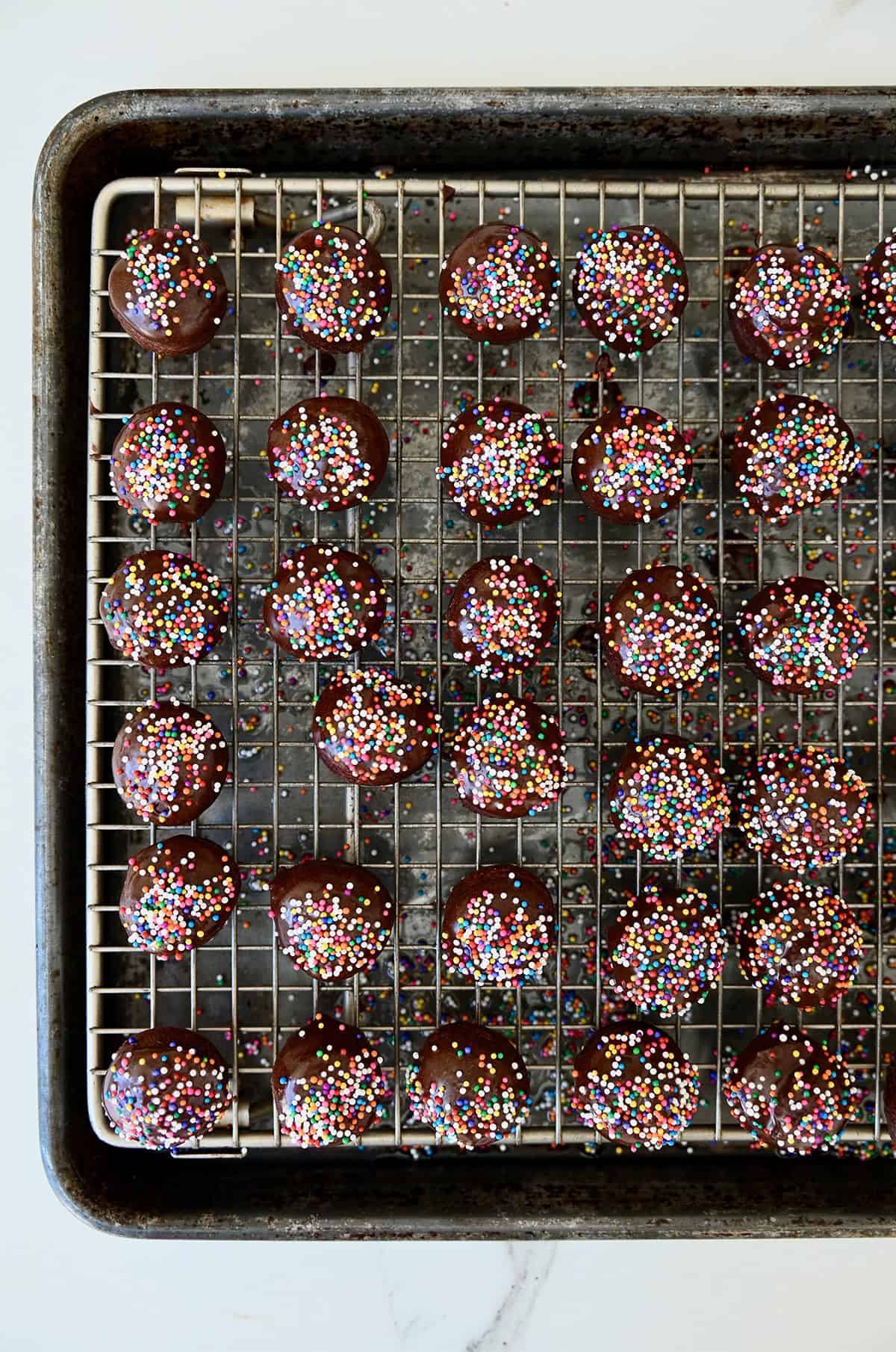 Chocolate glazed doughnuts with sprinkles on a wire rack.