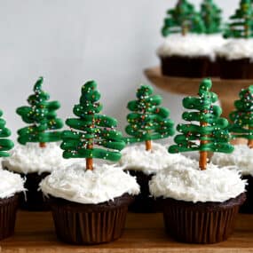 A "forest" of Chocolate Christmas Tree Cupcakes with Cream Cheese Frosting and pretzel/candy melt toppers