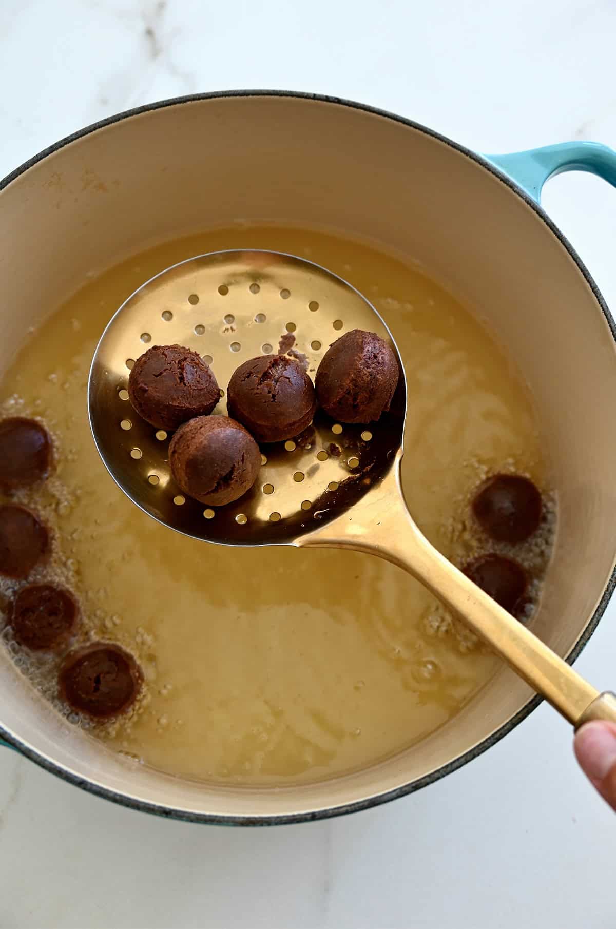Frying chocolate doughnuts in oil.