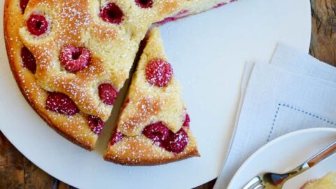 Top down view of Raspberry Cream Cheese Coffee Cake on white plate and glasses filled with orange juice