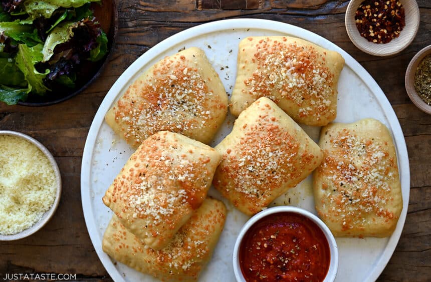 Easy homemade pizza pockets on a white plate next to a small bowl containing marinara sauce