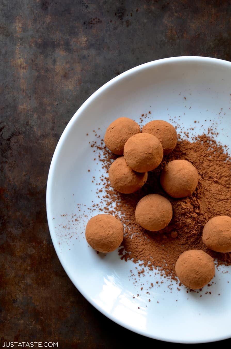 Chocolate truffles and cocoa powder on a white plate.