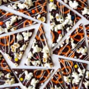 A top-down view of chocolate bark topped with popcorn, pretzels, M&Ms and sprinkles that's all drizzled with white chocolate.