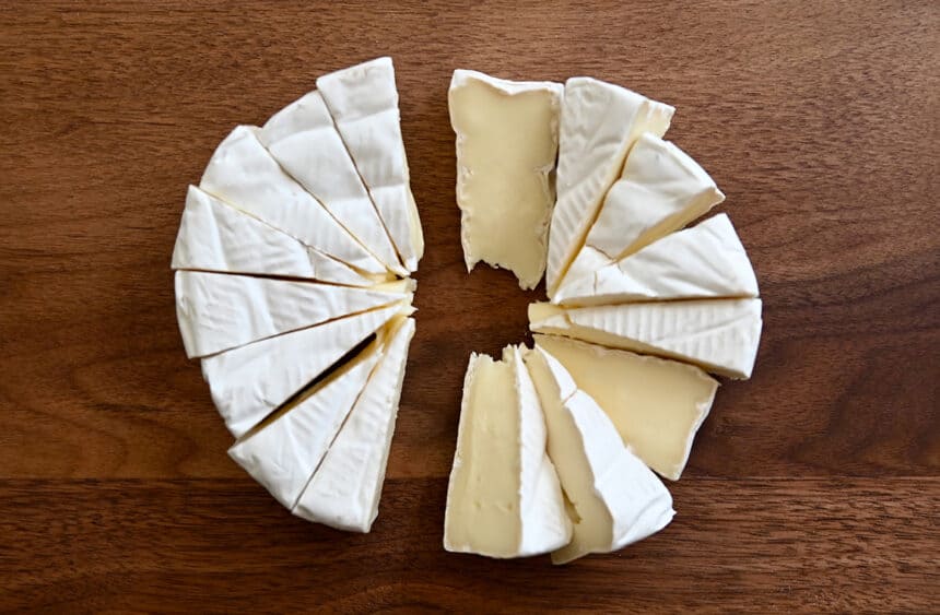 A top-down view of a brie wheel sliced into small wedges