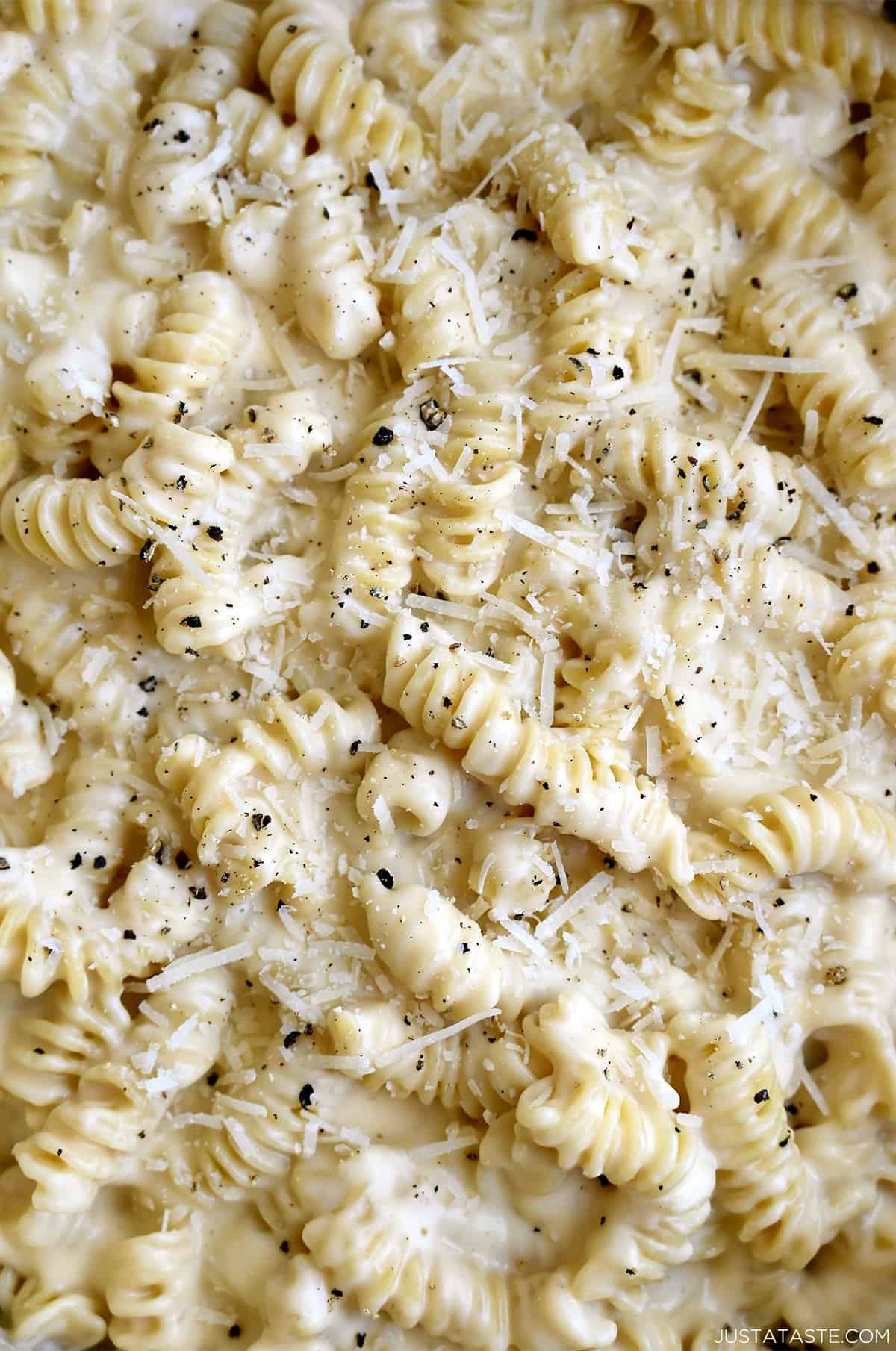Extra-cheesy macaroni and cheese garnished with shredded Parmesan and cracked black pepper.