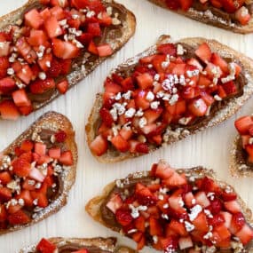 A top-down view of Strawberry Bruschetta starring Nutella, fresh strawberries and chopped walnuts