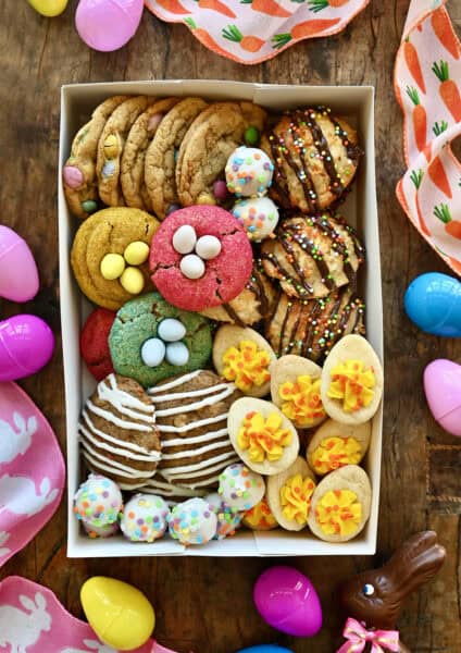 A white box containing Easter cookies surrounded by Easter eggs and ribbon.